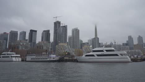 Luxury-Yachts-In-Toronto-Harbourfront,-Cn-Tower-Covered-By-Clouds