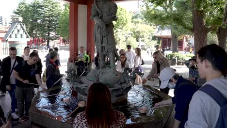 Gente-Tomando-Agua-Bendita-De-La-Fuente-De-Purificación-En-El-Templo-Senso-ji,-Asakusa