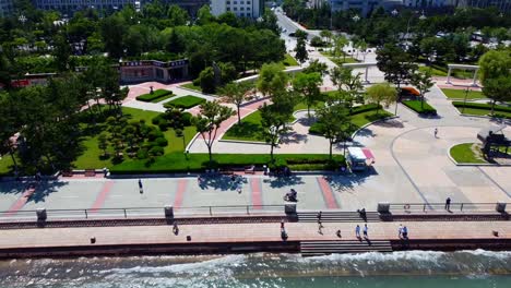 Left-panoramic-view-of-Xingfu-Park-in-Weihai,-China,-with-stunning-cityscape-and-lively-crowd-in-the-background