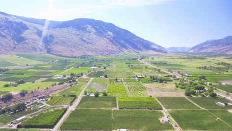 Drone-shot-over-the-valley-of-British-Columbia-with-stunning-green-crops-on-the-farmers-fields-surrounded-by-the-Rocky-mountains