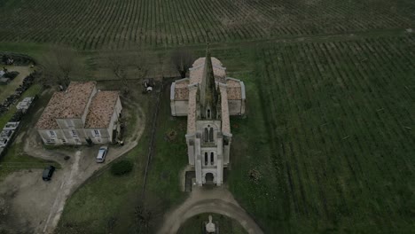 aerial-reveal-of-Saint-Michel-de-Fronsac-Church-Amid-Vines,-France
