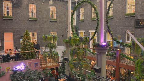 Innenaufnahme-Des-Berühmten-Powerscourt-Townhouse-Centre,-Das-Im-Dezember-In-Dublin,-Irland,-Weihnachtlich-Mit-Lichtern-Und-Künstlichen-Pflanzen-Mit-Besuchern-Geschmückt-Ist