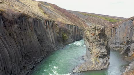 Beautiful-autumn-colours-in-basalt-Studlagil-canyon-in-East-Iceland---Aerial-shot