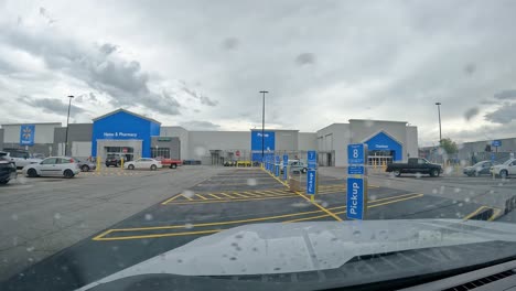 POV---Driving-thru-the-parking-lot-of-Walmart,-past-the-area-designated-for-customer-Pick-Up-on-a-cloudy,-rainy-day