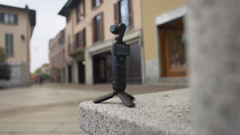 Osmo-Pocket-3-handheld-action-camera-with-gimbal-on-tripod-legs-outdoors,-time-lapse-photography