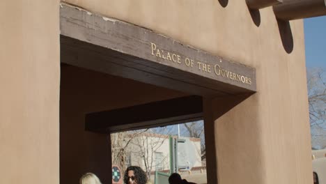 Palace-of-Governors-in-downtown-Santa-Fe,-New-Mexico-with-people-walking-by-and-video-tilting-down
