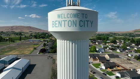 Aufsteigende-Drohnenaufnahme-Des-Wasserturms-Von-Benton-City-Mit-Mobilfunkverteilungstechnologie-An-Der-Spitze