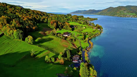 attersee-lake-with-autumn-trees,-clear-waters,-and-mountain-backdrop-drone-footage