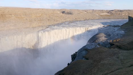 Majestuosa-Cascada-Dettifoss-En-Islandia-Con-Un-Poderoso-Flujo-De-Agua-Y-Niebla,-Con-Un-Pequeño-Arco-Iris