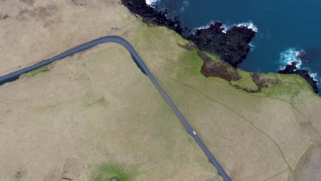 Aerial-shot-overhead-a-car-driving-along-the-coast-of-Vestmannaeyjar