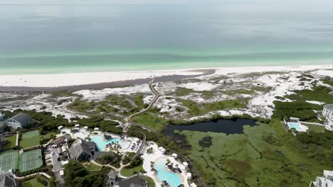 turning-to-right-motion-wide-view-of-ocean-side,-buildings,-pools,-tennis-courts,-lake,-woods,-blue-sky-across-street-from-prominence-on-30A-Florida-and-Water-sound-club