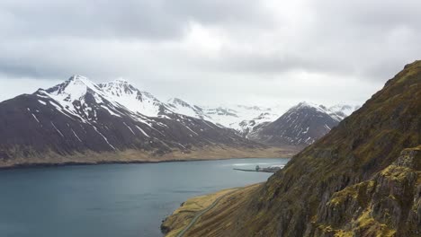 Vista-Aérea-De-Un-Majestuoso-Paisaje-Islandés,-Que-Muestra-Montañas-Cubiertas-De-Nieve-Y-Un-Sereno-Fiordo.
