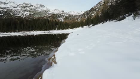 Snowy-banks-of-Palù-lake-in-Valmalenco,-Italy