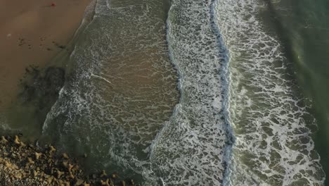 Luftaufnahme-Von-Oben-Nach-Unten-Von-Wasser-Und-Strand-Mit-Brechenden-Wellen-In-Mui-Ne,-Vietnam-Im-Goldenen-Morgenlicht