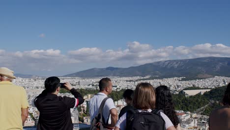 Tourist-group-watching-the-white-houses-of-Athens,-sightseeing-on-a-sunny-day,-Greece