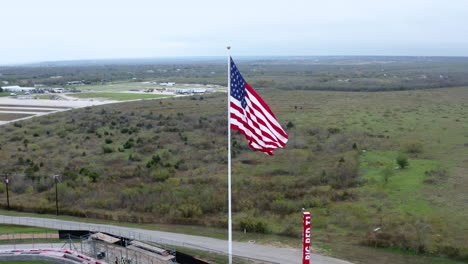 Day-time-overcast-drone-flying-around-United-States-US-Flag-in-Wind
