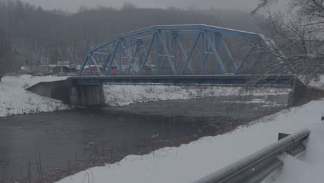 Blue-arched-steel-bridge-crossing-the-roundout-creek-on-a-snowy-day-in-Rosendale,-New-York