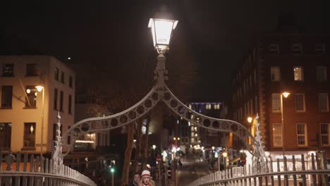 People-walking-on-the-Ha'penny-bridge-during-night,-close-up-lights