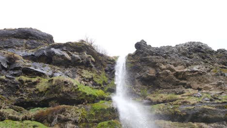 Secluded-waterfall-cascading-down-mossy-volcanic-rocks-in-the-rugged-Icelandic-landscape