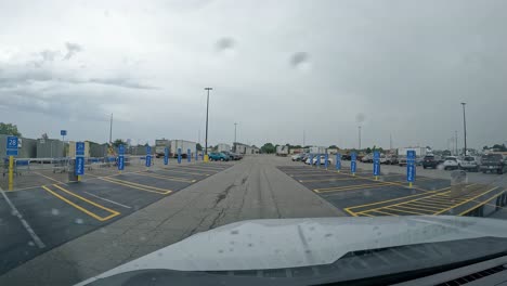 POV---Driving-thru-the-parking-lot-of-Walmart,-past-the-area-designated-for-customer-Pick-Up-on-a-cloudy,-rainy-day
