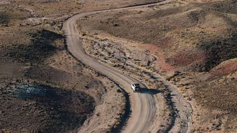 Off-road-vehicle-driving-along-unpaved-road-in-desert-of-Bentonite-Hills-in-Utah,-USA