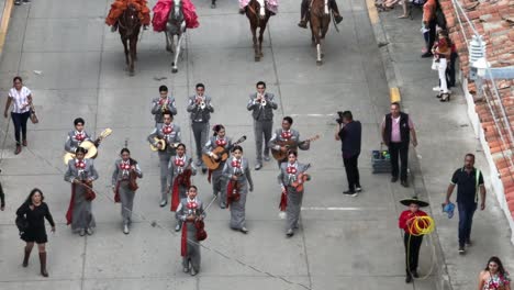 Mexican-Musician-Group-on-street-during-Mariachi-Festival-2023,-aerial-backwards-shot