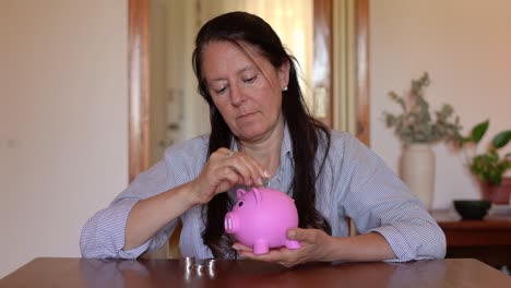 A-Woman-is-Putting-Coins-Into-the-Piggy-Bank---Close-Up