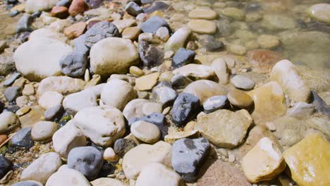 Slow-motion-shot-of-water-rushing-through-the-rocks-on-the-ground-on-a-bright-sunny-day