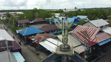Das-Schöne-Handdenkmal-Und-Die-örtlichen-Häuser-Stehen-Auf-Der-Spitze-Der-Stadt-Agats,-Asmat,-Papua,-Indonesien