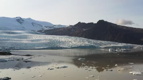 Vasto-Glaciar-Vatnajökull-En-Islandia-Con-Hielo-Y-Nieve-Relucientes-Bajo-Un-Cielo-Azul-Claro,-Reflejado-En-Un-Tranquilo-Lago-Glacial