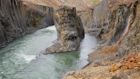 Un-Río-Caudaloso-Fluye-A-Través-De-Un-Espectacular-Cañón-Islandés-Con-Distintivas-Formaciones-De-Columnas-De-Basalto-Y-Un-Terreno-Accidentado,-Que-Muestra-El-Poder-De-La-Naturaleza.