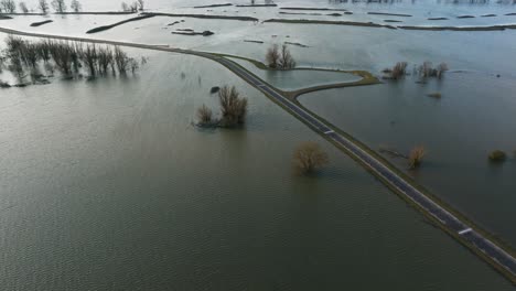 Aerial-dolly-forward-view-of-a-road-surrounded-by-flooded-fields-along-the-Waal-River-in-the-Netherlands-after-heavy-rains-inundated-Northern-Europe