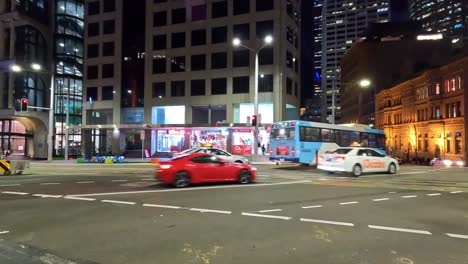 Sydney-Traffic-Passing-Through-Busy-George-Street-Intersection-At-Night