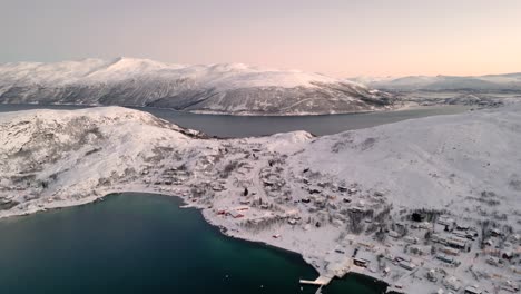 Aerial-establishing-shot-of-the-small-village-ersfjordvegen-surrounded-by-snow