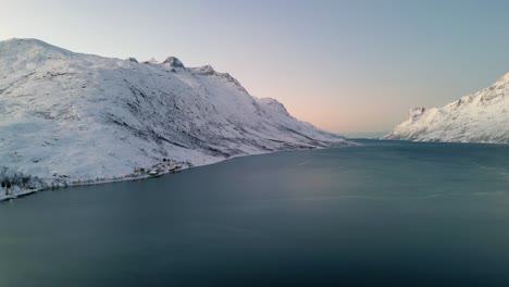 Aerial-establishing-shot-of-a-frozen-lake-between-mountains-in-ersfjordvegen