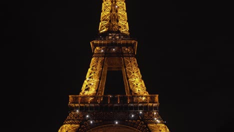 Brillantes-Niveles-Superiores-De-La-Torre-Eiffel-Por-La-Noche-En-Champ-De-Mars