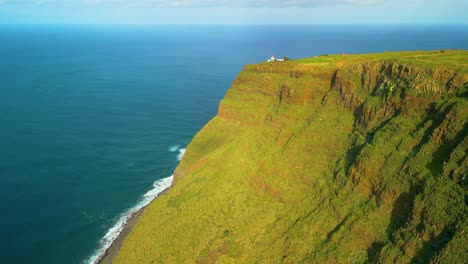 Luftaufnahme-Einer-Grünen-Klippe-Mit-Gebäude-Am-Rand-Und-Blauem-Atlantik-Auf-Madeira-Bei-Sonnenuntergang