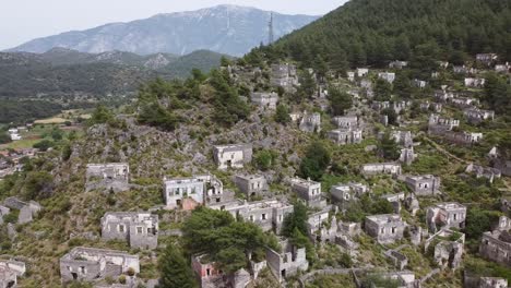Drone-moving-around-the-abandoned-houses-of-Kayaköy,-a-UNESCO-World-Friendship-and-Peace-Village-in-the-district-of-Fethiye,-Muğla-Province,-Turkey