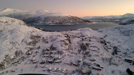 Aerial-establishing-shot-of-small-cabins-built-in-ersfjordvegen-beside-a-lake