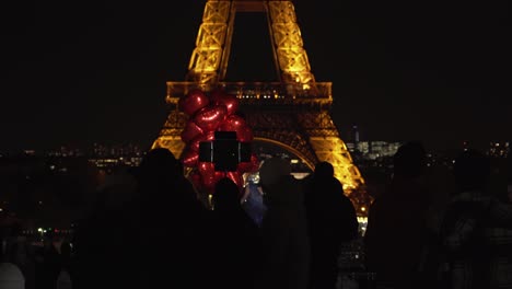 Photographer-Takes-Photos-of-Young-Girl-with-Red-Balloons-in-Front-of-Eiffel-Tower-at-Night-in-Place-du-Trocadero