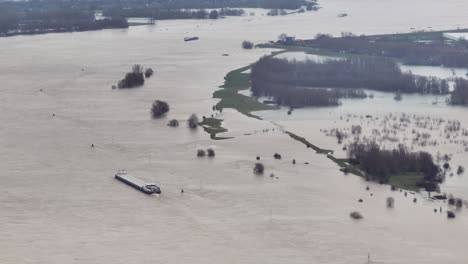 Wide-aerial-view-of-a-ship-steaming-on-the-Waal-River-near-Gorinchem-Netherlands-after-heavy-rains-caused-the-river-to-overflow-its-banks-and-inundate-farms-and-communities