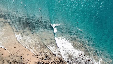 Top-Down-View-Of-Surfers-Floating-In-The-Turquoise-Ocean-In-Noosa-Shire,-Queensland,-Australia---Drone-Shot