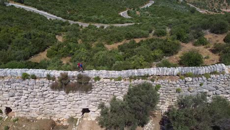 Steady-drone-shot-of-a-hiker-waling-on-top-of-a-wall-along-the-Lycian-Way,-a-marked-long-distance-hiking-trail-in-southwestern-Turkey