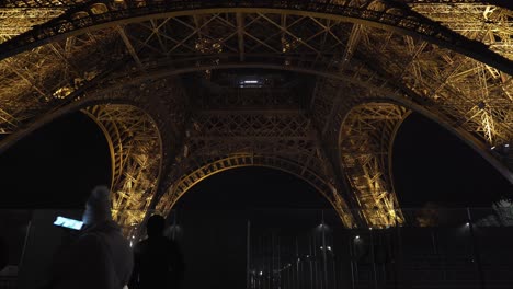 Gente-Caminando-Cerca-De-La-Torre-Eiffel-Por-La-Noche-En-El-Tour-Del-Jardín-Eiffel