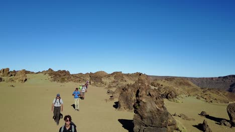 Toma-Aérea-Sobre-Un-Grupo-De-Turistas-Caminando-Por-El-Paisaje-Volcánico-Marciano-De-Las-Islas-Canarias.