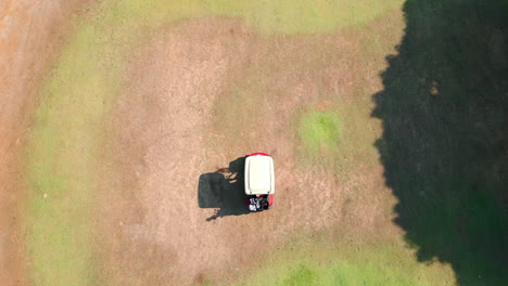 Aerial-drone-shot-of-gold-cart-driving-on-fairway-of-golf-course