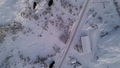 Top-down-shot-overhead-cars-driving-through-the-snowy-village-of-ersfjordvegen