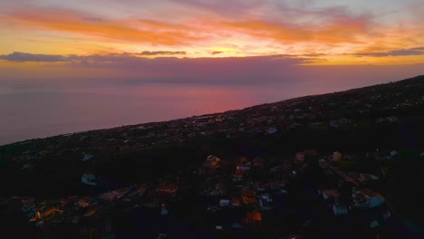 Aerial-backwards-shot-of-Portuguese-village-on-hill-with-Atlantic-ocean-view-during-sunset-time-on-Madeira-Island