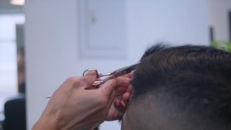 Over-comb-scissors-being-used-on-front-side-of-head-to-trim-hair,-filmed-from-left-side-of-scissors-in-closeup-style