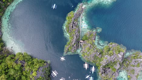 Karst-outcrops-and-tour-boats-at-Twin-Lagoon,-Coron,-Aerial-top-down